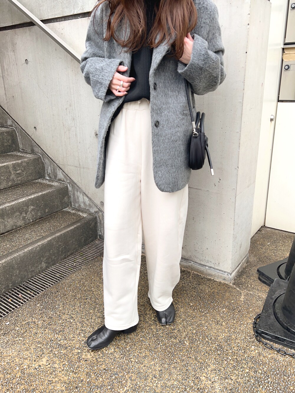 グレー系のテーラードジャケット、ホワイト系のスウェットパンツ、ブラック系のショルダーバッグを着用したレディースの冬コーディネートの5枚目の写真