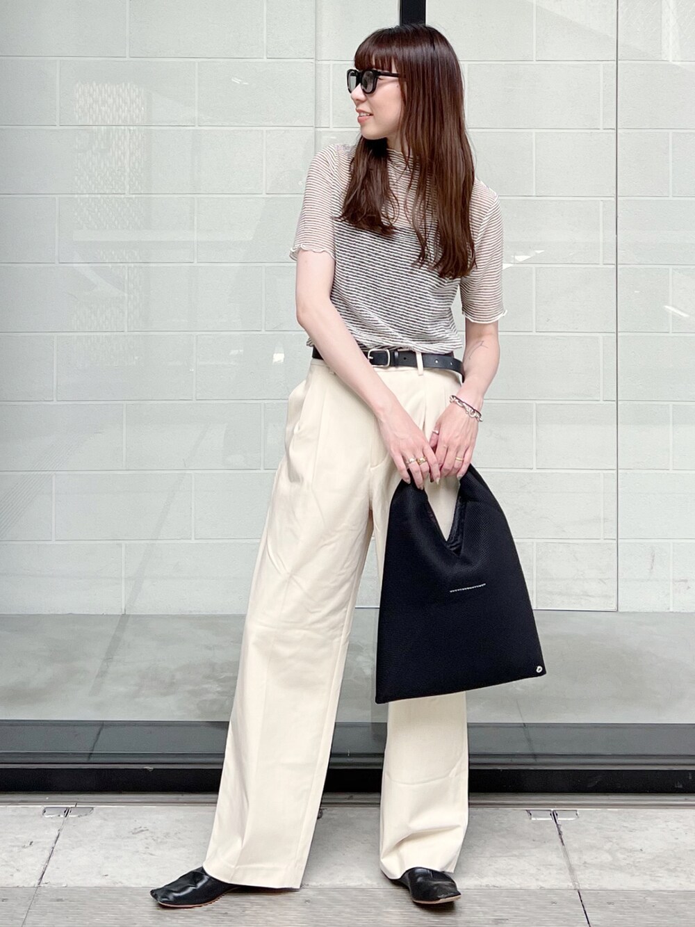 ブラック系のTシャツ/カットソー、ブラック系のトートバッグ、ホワイト系のパンツを着用したレディースの夏コーディネートの2枚目の写真
