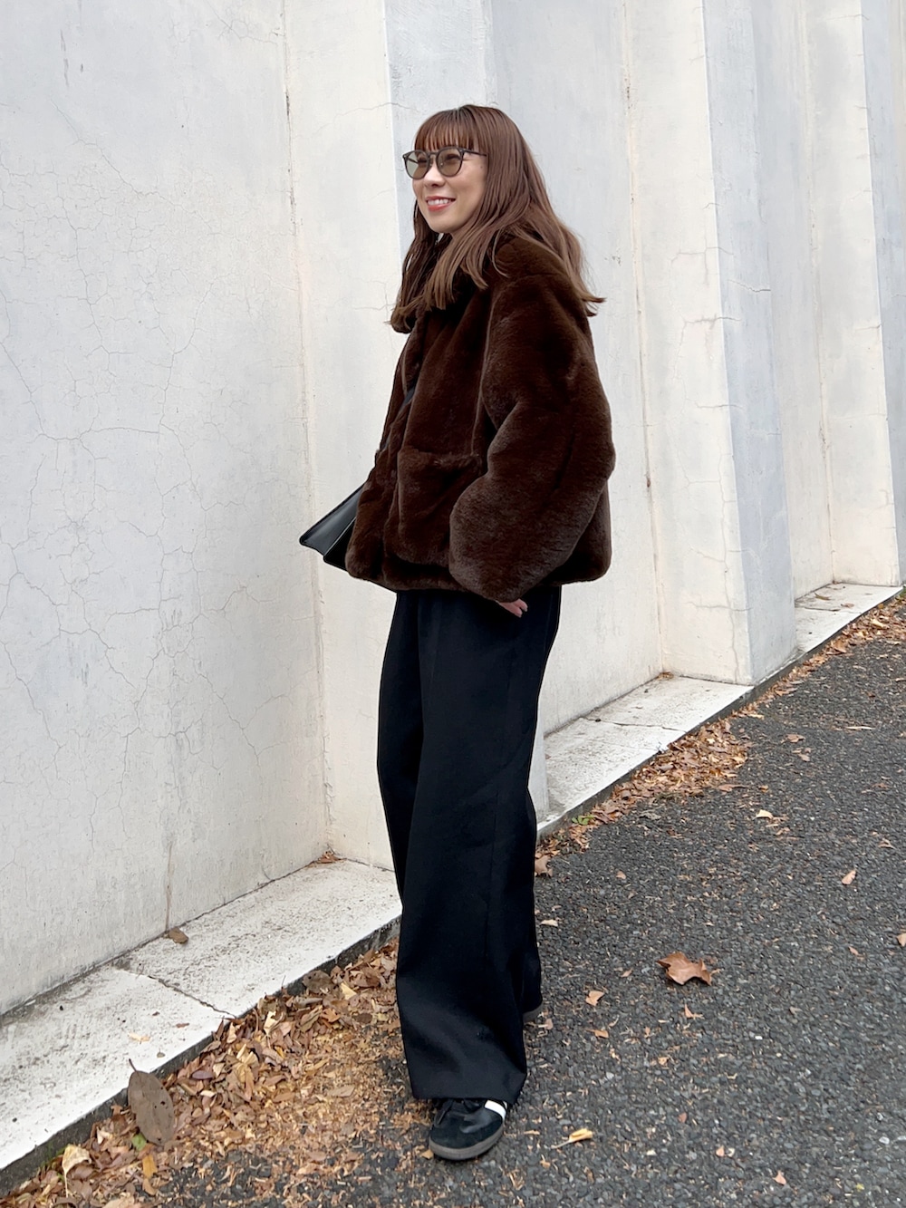 ブラウン系のブルゾン、ブラック系のショルダーバッグ、ホワイト系のTシャツ/カットソーを着用したレディースの冬コーディネートの3枚目の写真