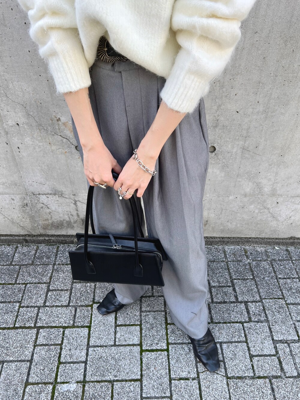 ホワイト系のニット/セーター、グレー系のスラックス、ブラック系のハンドバッグを着用したレディースの秋コーディネートの5枚目の写真