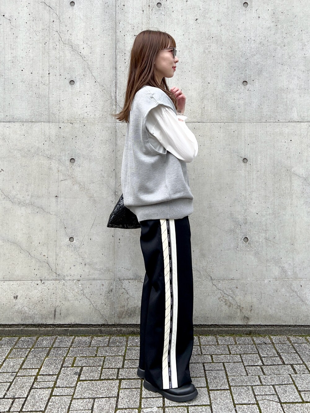 ホワイト系のTシャツ/カットソー、グレー系のニット/セーター、ブラック系のスラックスを着用したレディースの春コーディネートの3枚目の写真