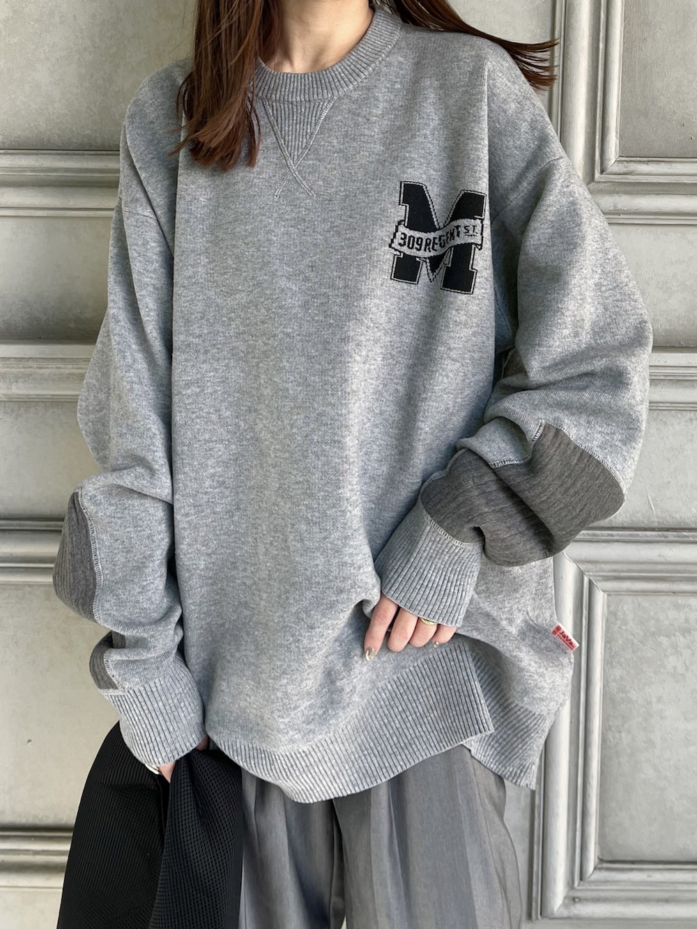 グレー系のニット/セーター、ブラック系のトートバッグ、グレー系のスラックスを着用したレディースの秋コーディネートの4枚目の写真