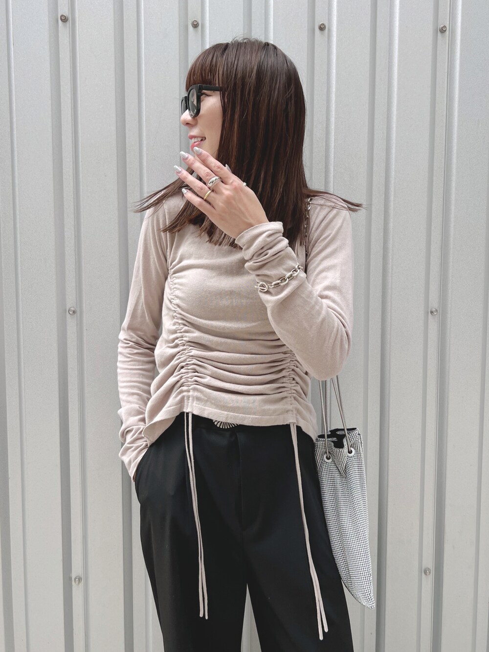 グレー系のニット/セーター、シルバー系のショルダーバッグ、ブラック系のパンツを着用したレディースの秋コーディネートの4枚目の写真