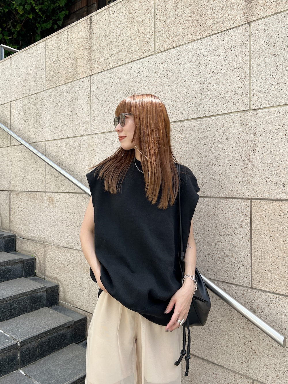 ブラック系のニット/セーター、ベージュ系のその他パンツ、ブラック系のサンダルを着用したレディースの夏コーディネートの4枚目の写真