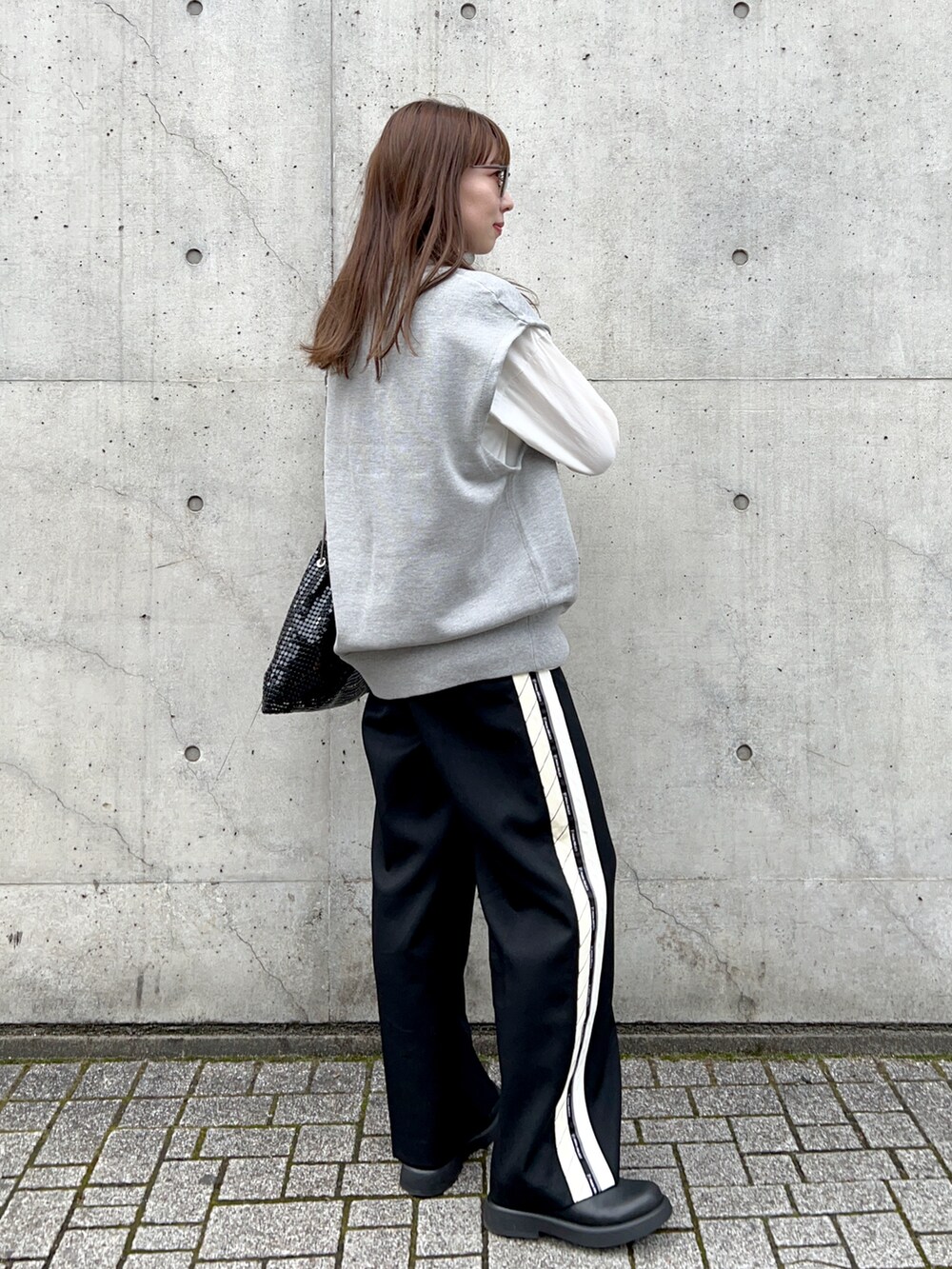 ホワイト系のTシャツ/カットソー、グレー系のニット/セーター、ブラック系のスラックスを着用したレディースの春コーディネートの4枚目の写真