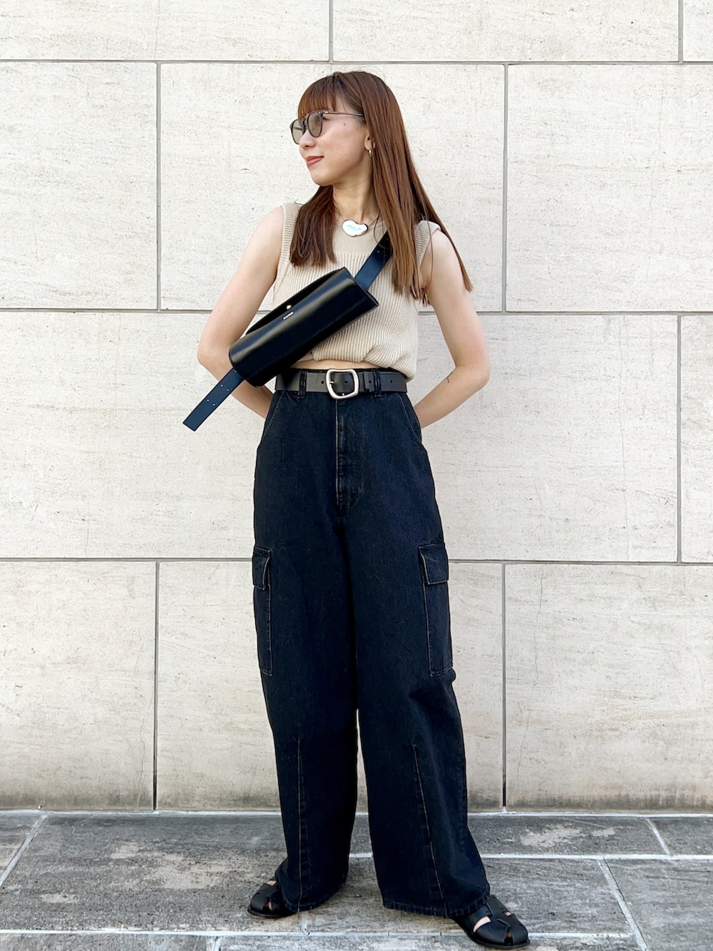 ベージュ系のニット/セーター、グレー系のデニムパンツ、ブラック系のショルダーバッグを着用したレディースの夏コーディネートの2枚目の写真