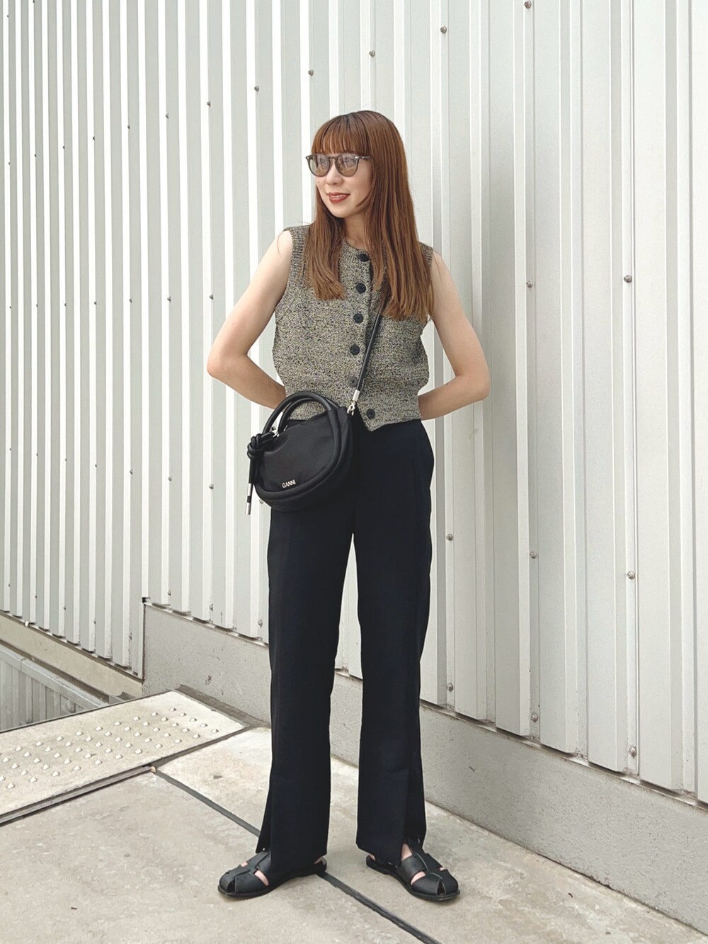 ブラック系のベスト、ブラック系のショルダーバッグ、ブラック系のパンツを着用したレディースの夏コーディネートの2枚目の写真