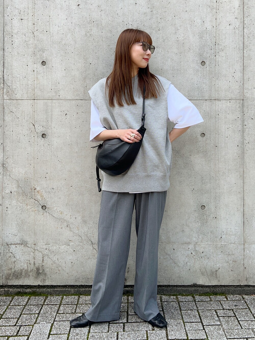グレー系のニット/セーター、ブラック系のスリッポン、ホワイト系のTシャツ/カットソーを着用したレディースの春コーディネートの2枚目の写真