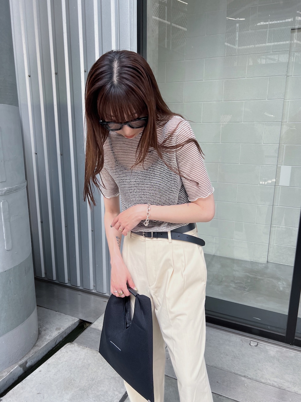 ブラック系のTシャツ/カットソー、ブラック系のトートバッグ、ホワイト系のパンツを着用したレディースの夏コーディネートの3枚目の写真