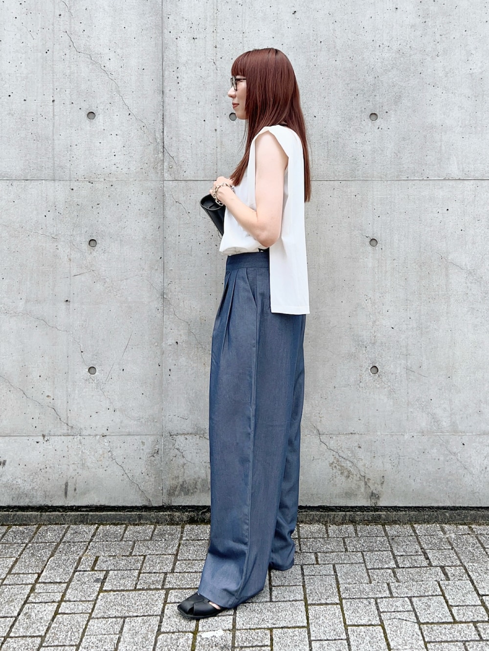 ブルー系のスラックス、ホワイト系のタンクトップ、ブラック系のショルダーバッグを着用したレディースの夏コーディネートの3枚目の写真