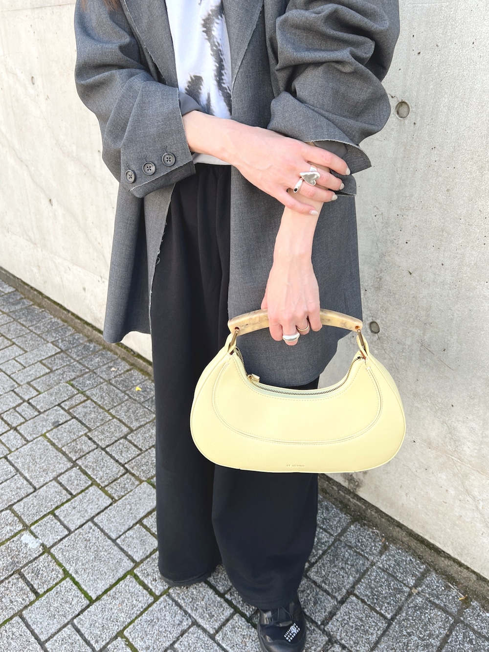 グレー系のテーラードジャケット、ホワイト系のTシャツ/カットソー、イエロー系のハンドバッグを着用したレディースの春コーディネートの5枚目の写真
