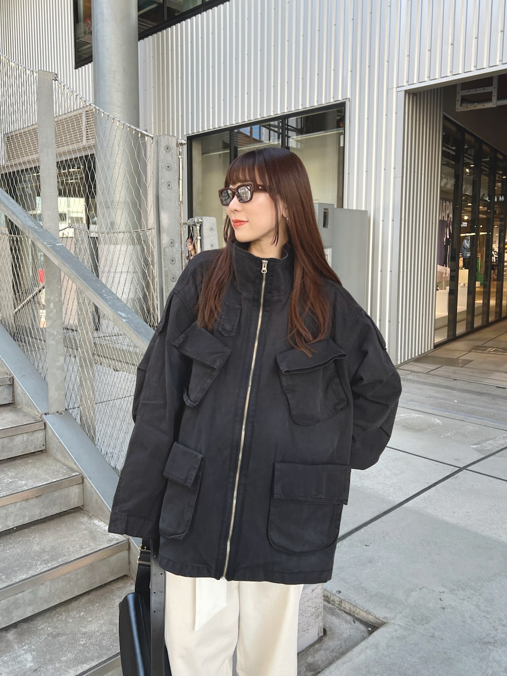 ブラック系のジャケット/アウター、ホワイト系のチノパンツ、ブラック系のショルダーバッグを着用したレディースの春コーディネートの3枚目の写真