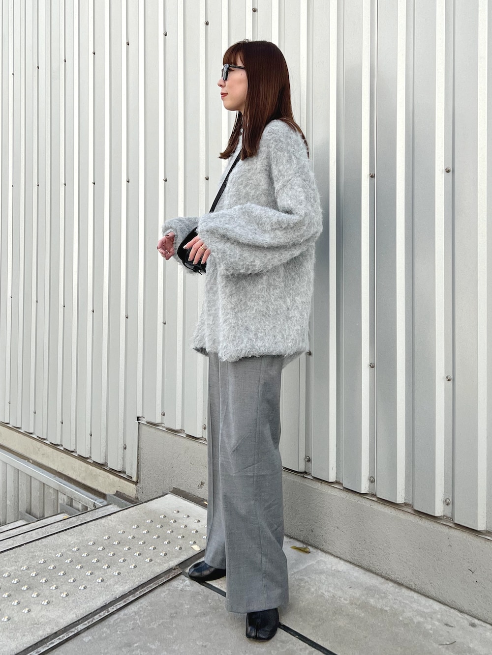 グレー系のニット/セーター、ブラック系のショルダーバッグ、グレー系のスラックスを着用したレディースの冬コーディネートの3枚目の写真