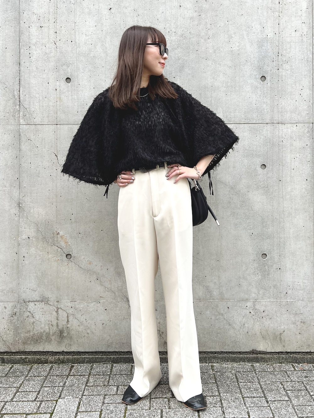 ブラック系のシャツ/ブラウス、ブラック系のショルダーバッグ、ホワイト系のスラックスを着用したレディースの秋コーディネートの2枚目の写真