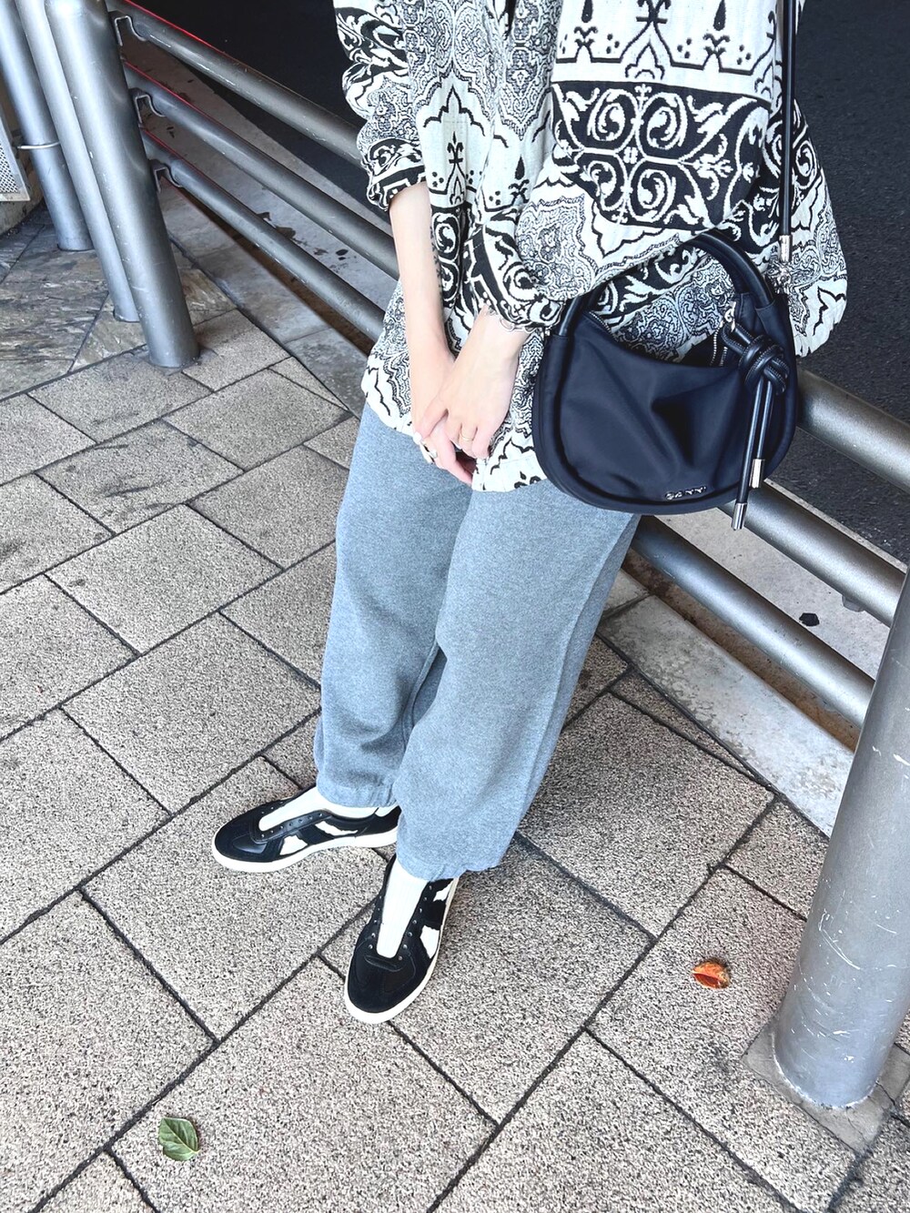 グレー系のパンツ、ブラック系のショルダーバッグ、ブラック系のスニーカーを着用したレディースの秋コーディネートの4枚目の写真
