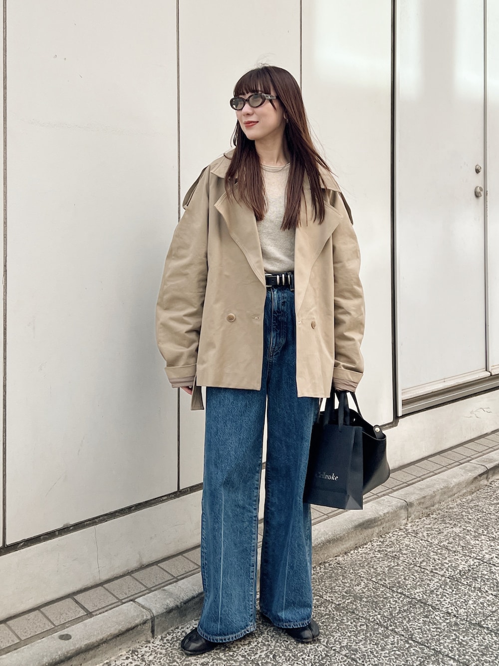 ベージュ系のトレンチコート、ブルー系のデニムパンツ、ブラック系のブーツを着用したレディースの春コーディネートの2枚目の写真