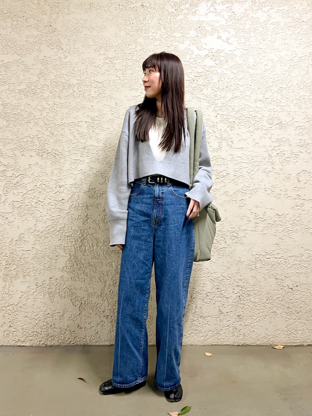 グレー系のニット/セーター、ブルー系のデニムパンツ、ブラック系のブーツを着用したレディースの冬コーディネートの2枚目の写真