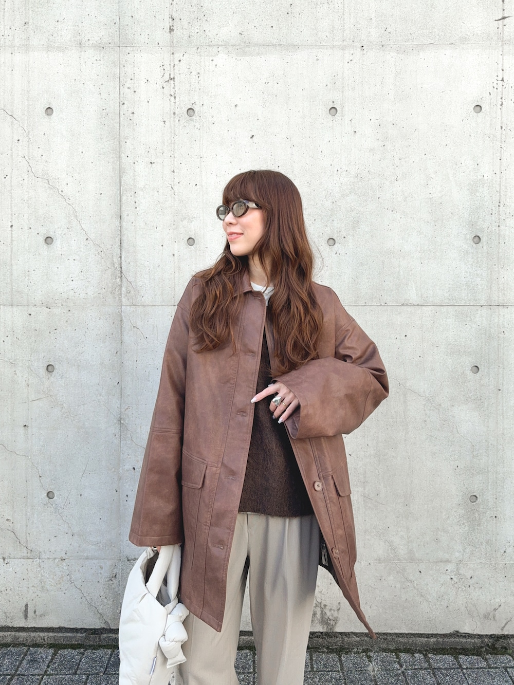 ブラウン系のニット/セーター、ベージュ系のパンツ、ベージュ系のハンドバッグを着用したレディースの秋コーディネートの4枚目の写真