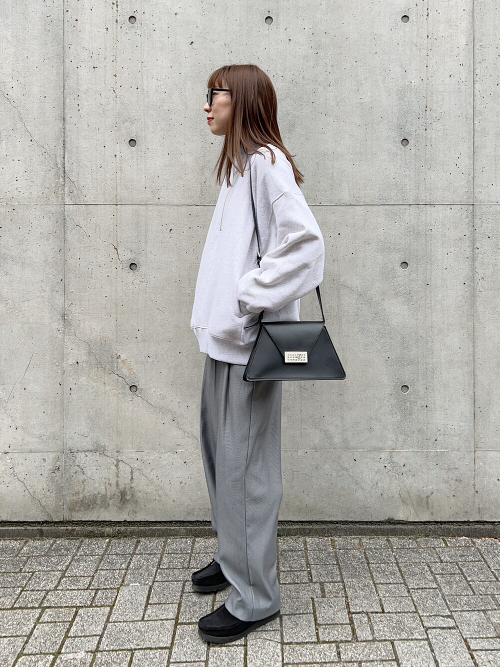 グレー系のスウェット、グレー系のスラックス、ブラック系のモカシン/デッキシューズを着用したレディースの冬コーディネートの2枚目の写真