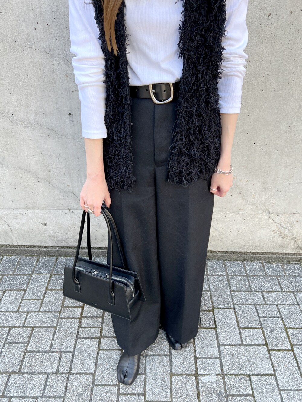 ブラック系のベスト、グレー系のその他パンツ、ブラック系のブーツを着用したレディースの春コーディネートの5枚目の写真