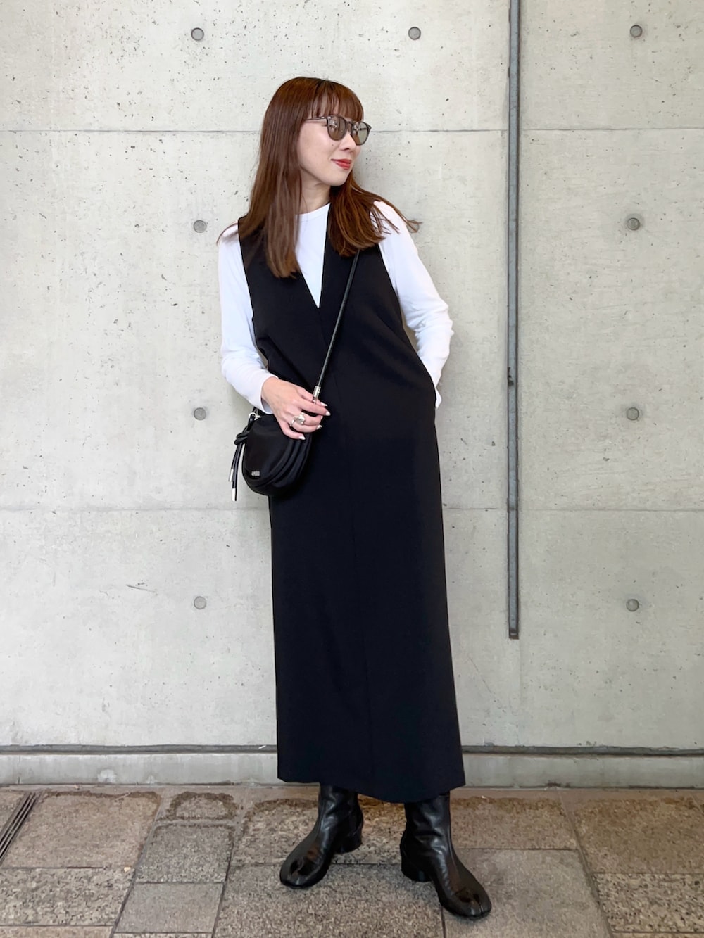 ブラック系のワンピース、ホワイト系のTシャツ/カットソー、ブラック系のハンドバッグを着用したレディースの冬コーディネートの2枚目の写真