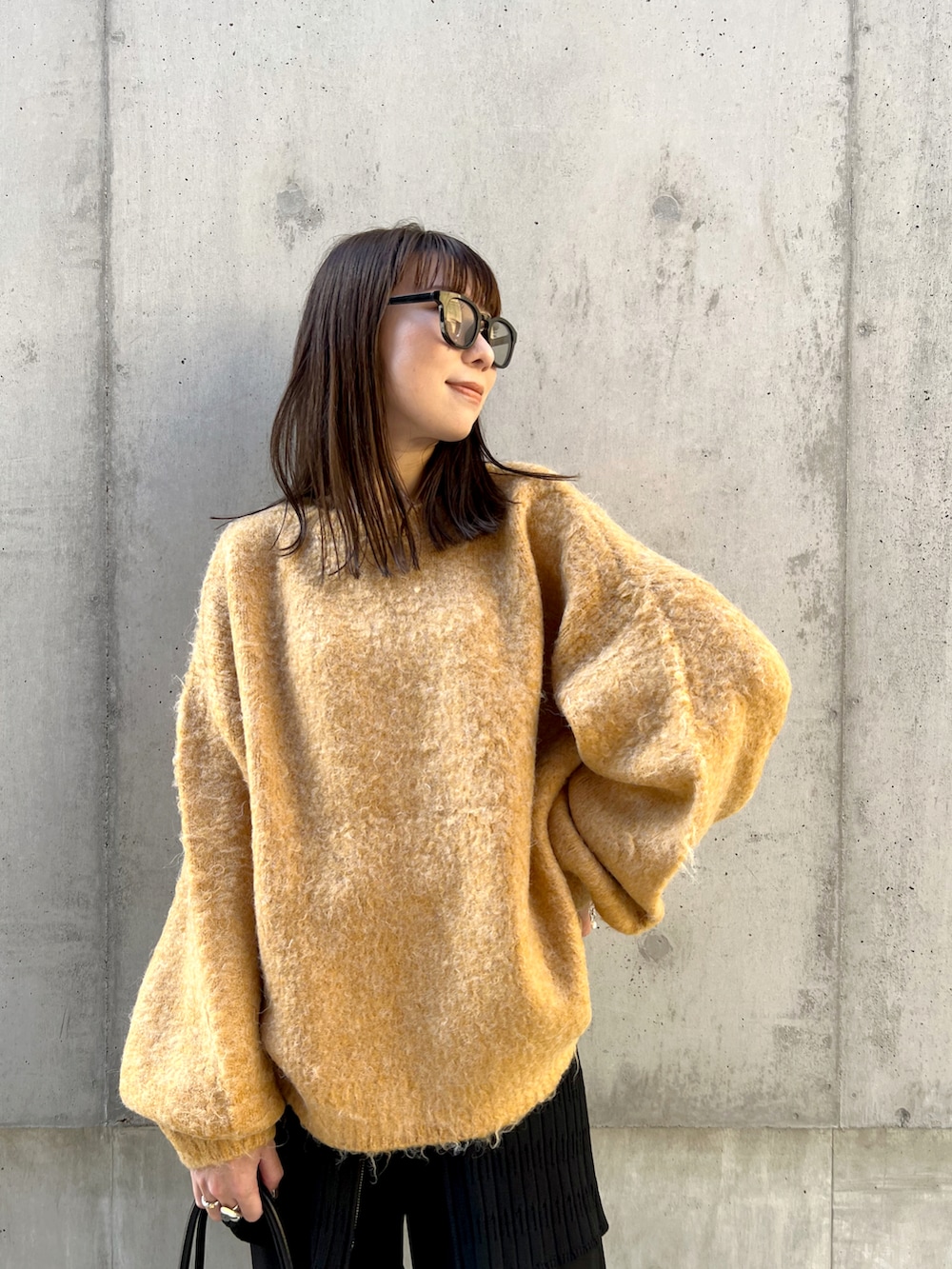 イエロー系のカーディガン/ボレロ、ブラック系のスラックス、ブラック系のハンドバッグを着用したレディースの秋コーディネートの4枚目の写真