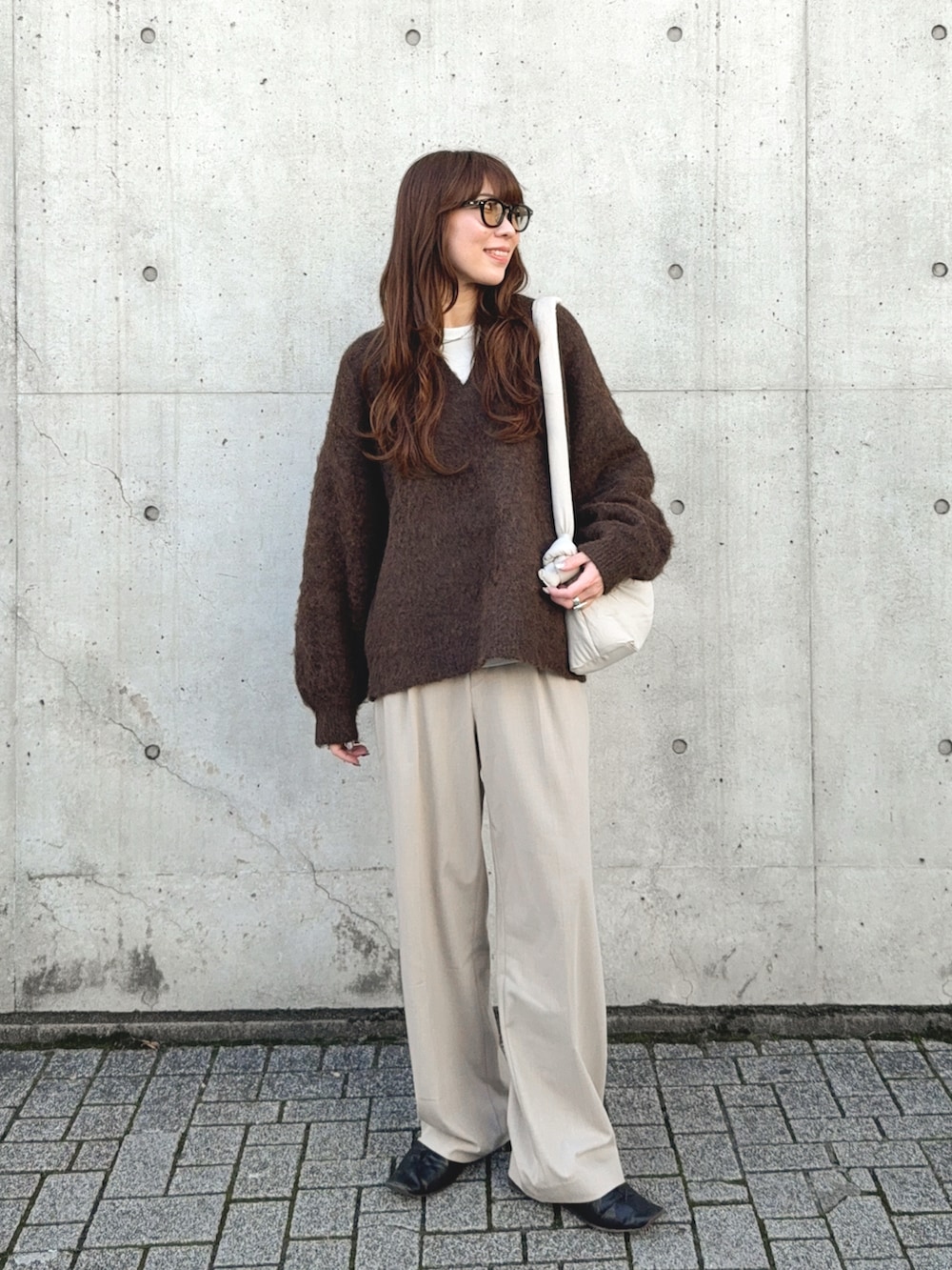 ブラウン系のニット/セーター、ベージュ系のパンツ、ベージュ系のハンドバッグを着用したレディースの秋コーディネートの2枚目の写真
