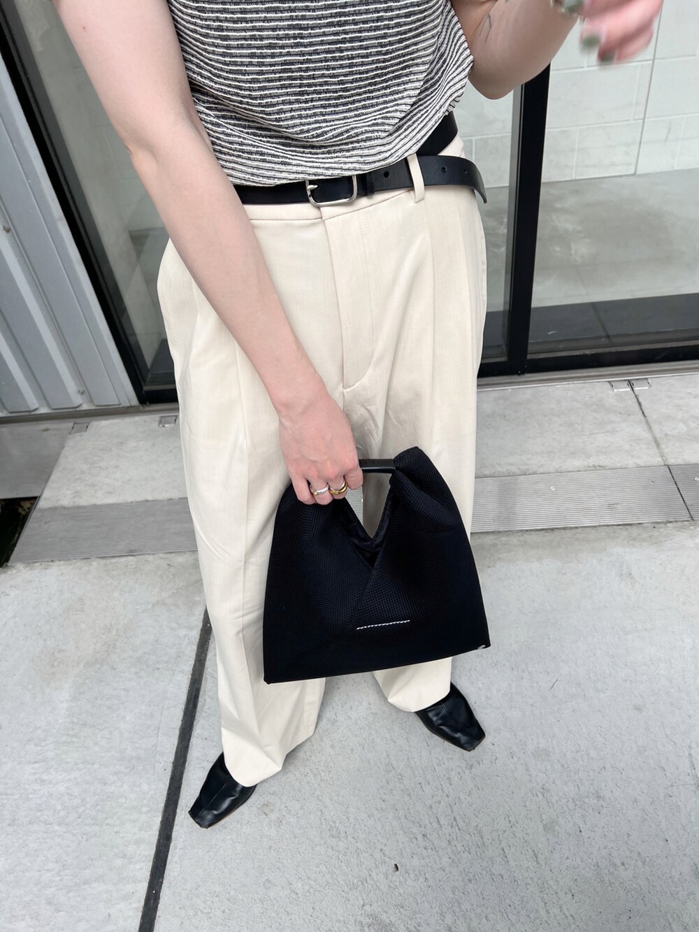 ブラック系のTシャツ/カットソー、ブラック系のトートバッグ、ホワイト系のパンツを着用したレディースの夏コーディネートの4枚目の写真