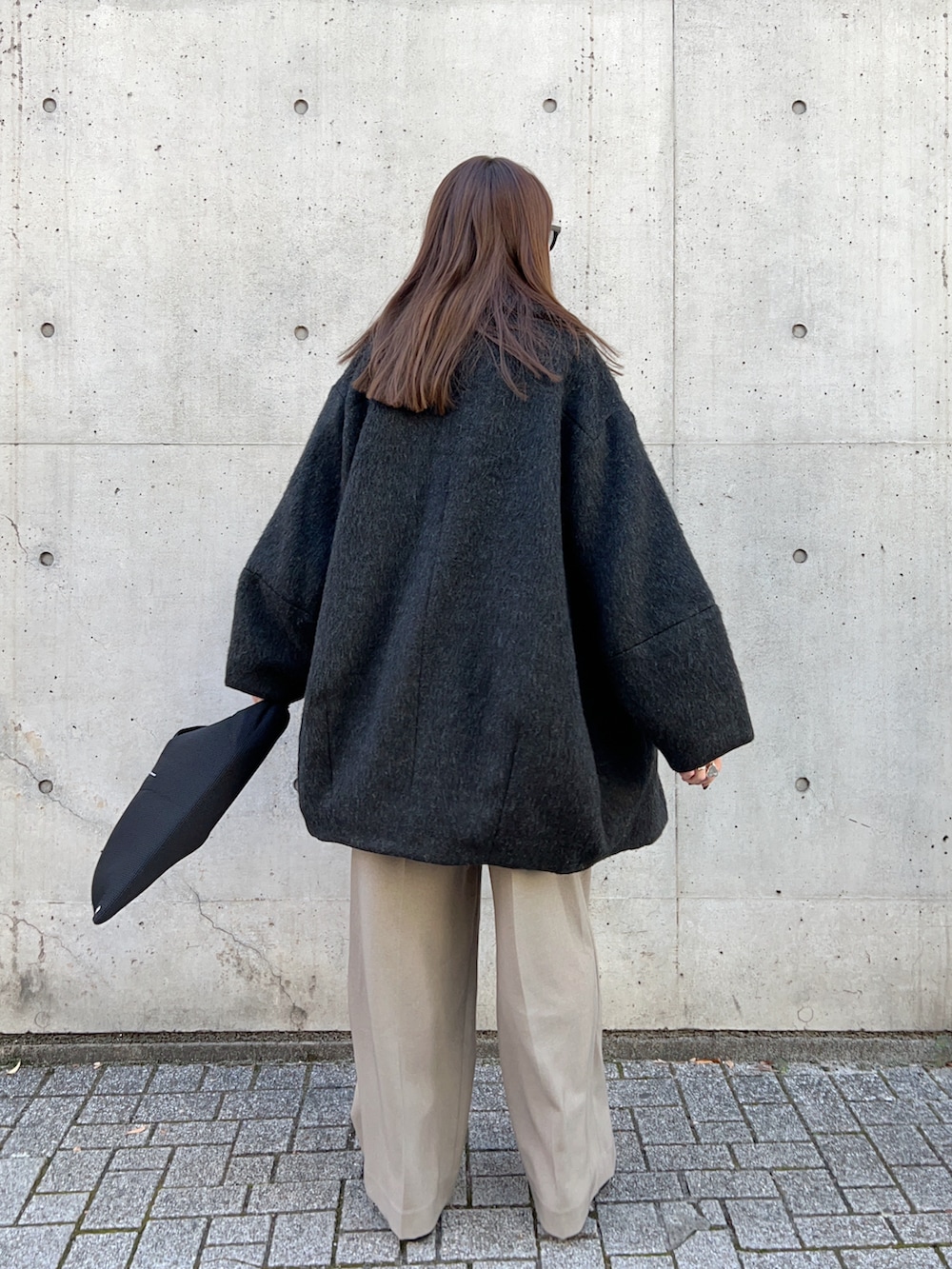 ブラック系のピーコート、ホワイト系のニット/セーター、ベージュ系のその他パンツを着用したレディースの冬コーディネートの4枚目の写真