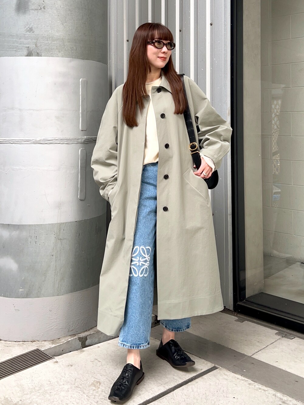グリーン系のステンカラーコート、ホワイト系のTシャツ/カットソー、ブルー系のデニムパンツを着用したレディースの春コーディネートの2枚目の写真