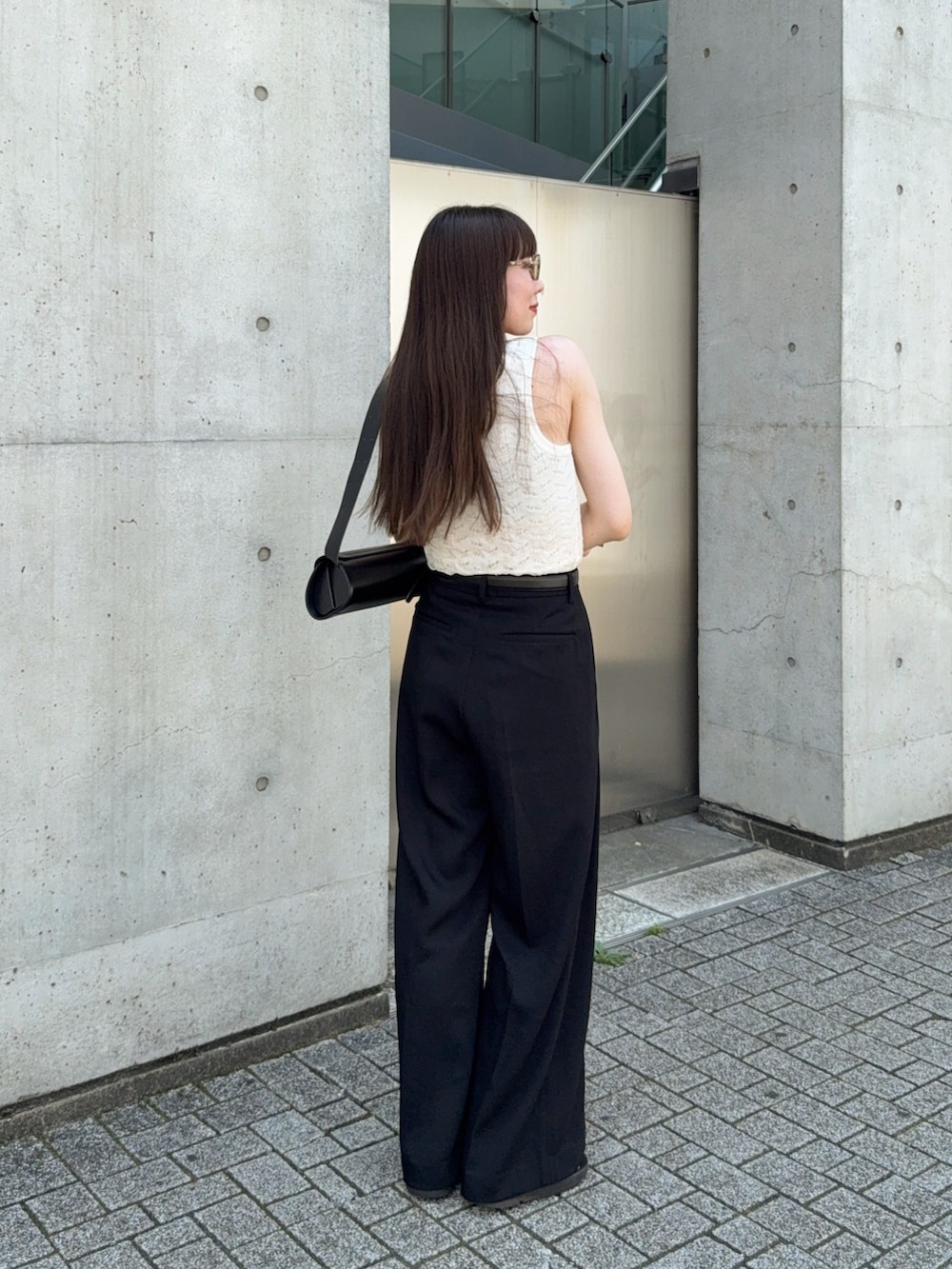 ホワイト系のタンクトップ、ブラック系のスラックス、ブラック系のサンダルを着用したレディースの夏コーディネートの3枚目の写真