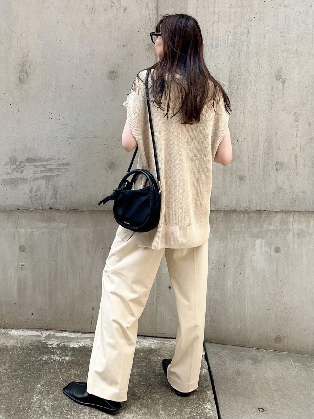 ホワイト系のパンツ、ブラック系のスリッポン、ベージュ系のトップスを着用したレディースの夏コーディネートの3枚目の写真