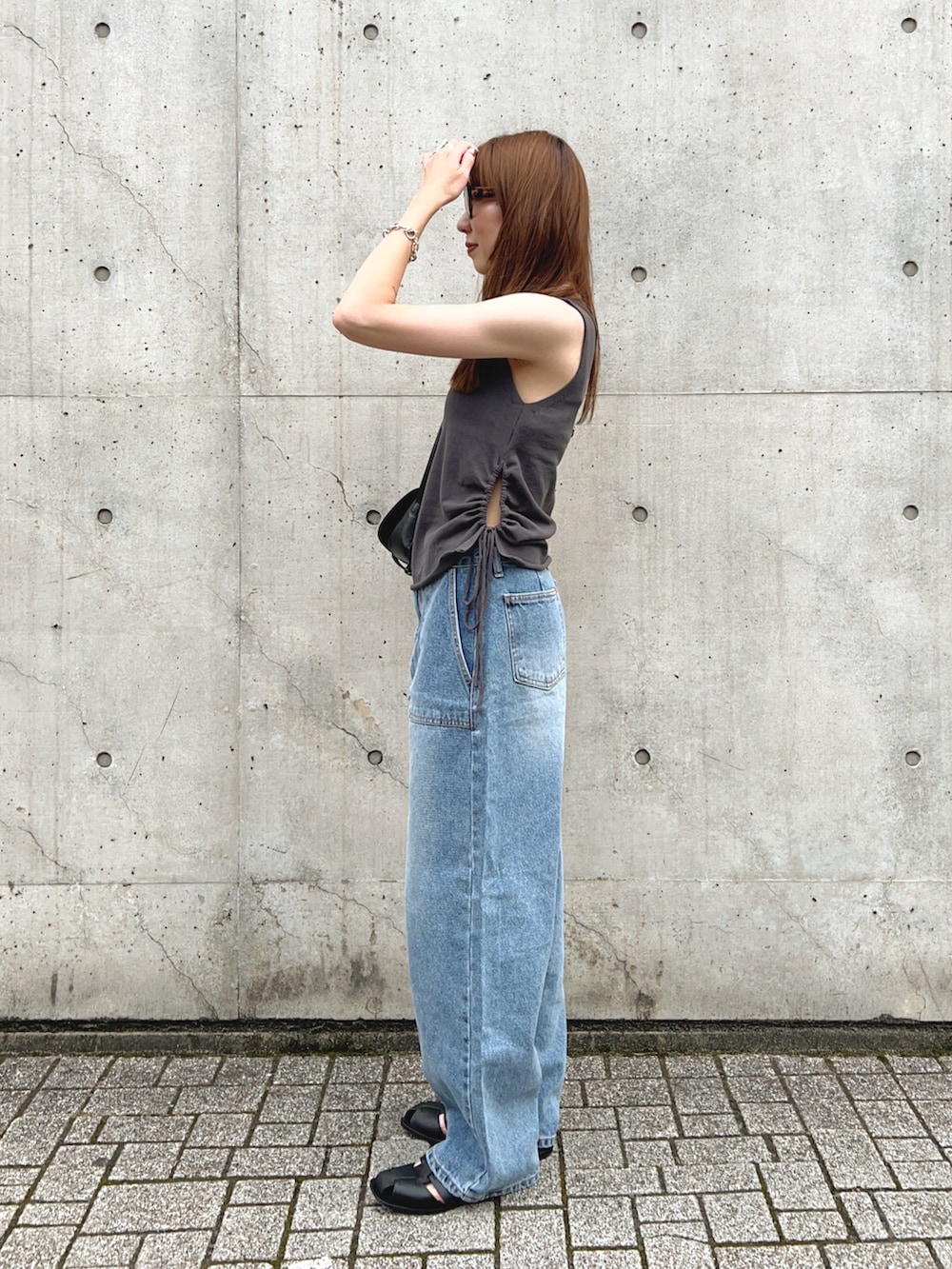 ブラック系のサンダル、グレー系のトップス、ブルー系のデニムパンツを着用したレディースの夏コーディネートの3枚目の写真