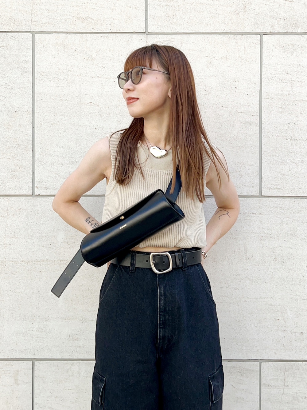 ベージュ系のニット/セーター、グレー系のデニムパンツ、ブラック系のショルダーバッグを着用したレディースの夏コーディネートの4枚目の写真