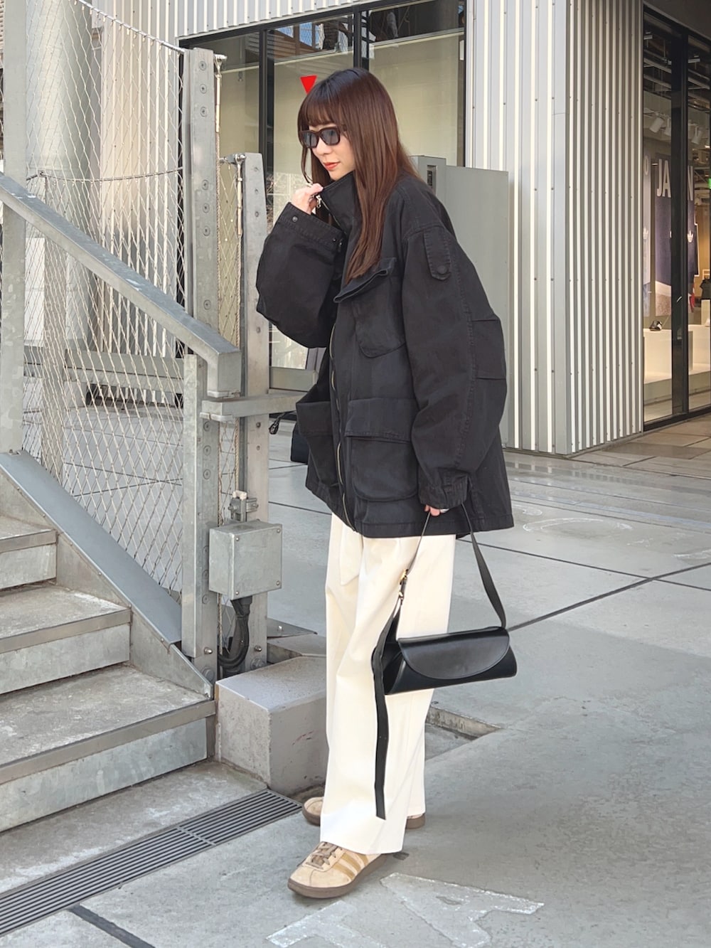 ブラック系のジャケット/アウター、ホワイト系のチノパンツ、ブラック系のショルダーバッグを着用したレディースの春コーディネートの2枚目の写真
