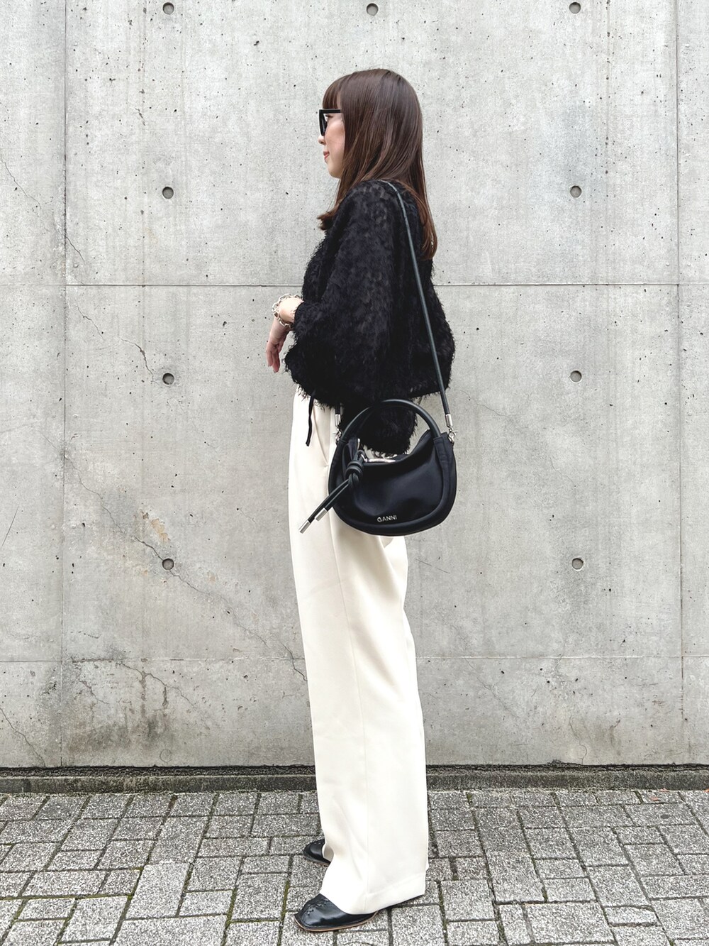 ブラック系のシャツ/ブラウス、ブラック系のショルダーバッグ、ホワイト系のスラックスを着用したレディースの秋コーディネートの3枚目の写真