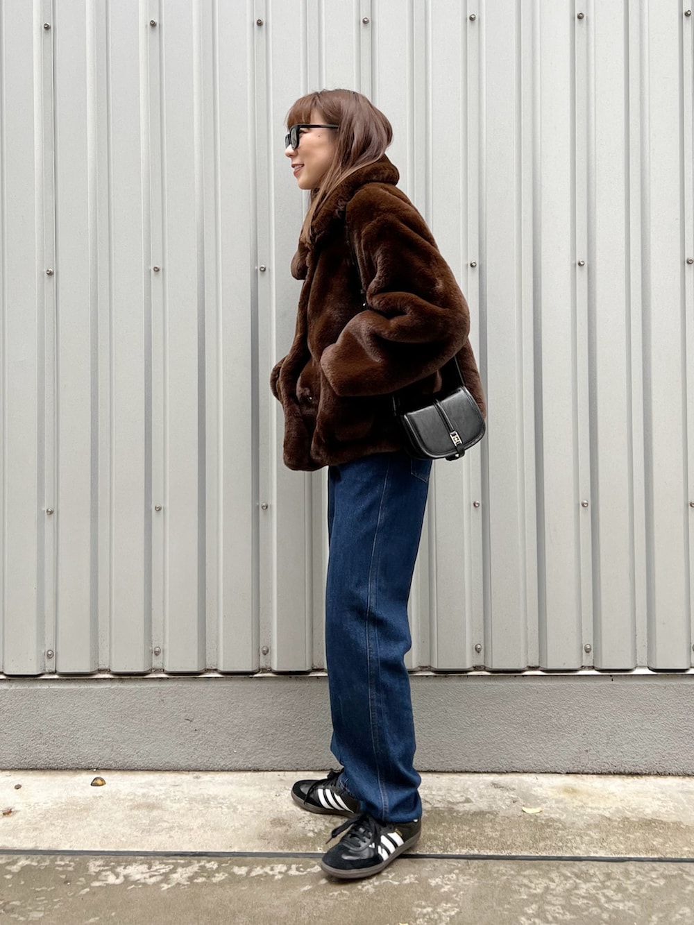 ブラウン系のブルゾン、ブルー系のデニムパンツ、ブラック系のスニーカーを着用したレディースの冬コーディネートの3枚目の写真