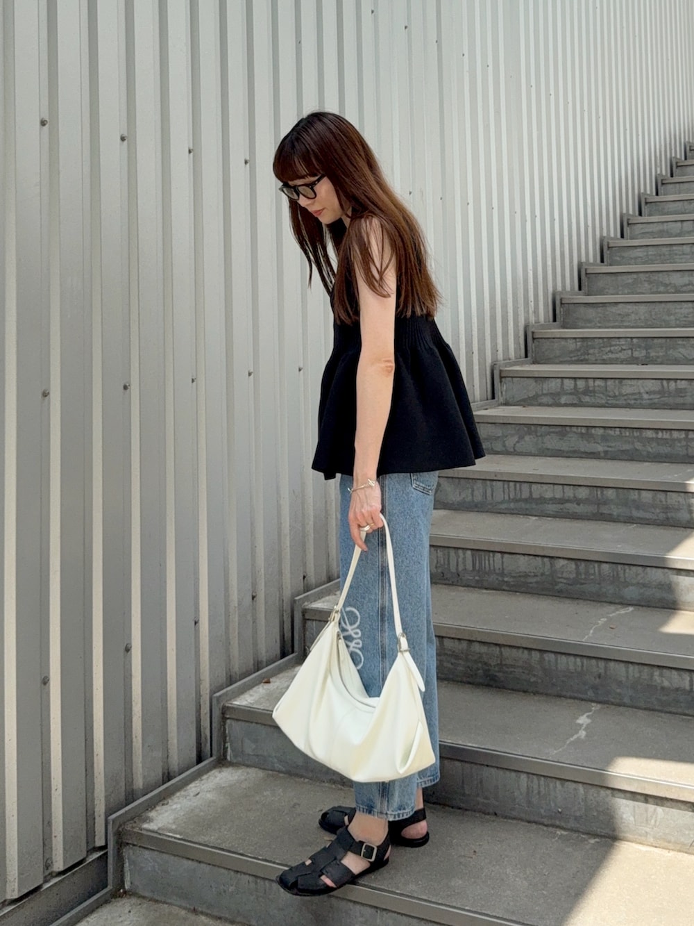 ブラック系のニット/セーター、ブラック系のサンダル、ブルー系のデニムパンツを着用したレディースの夏コーディネートの3枚目の写真