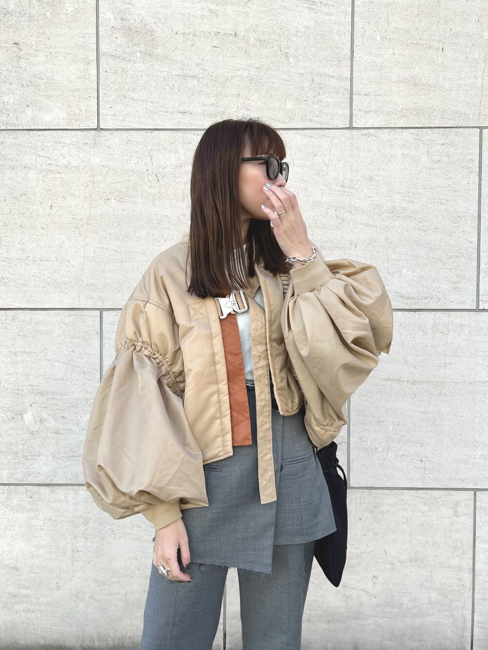 ベージュ系のMA-1、グレー系のスラックス、ブラック系のブーツを着用したレディースの秋コーディネートの5枚目の写真