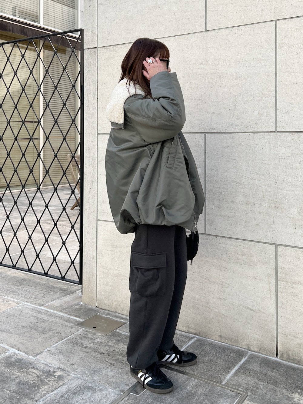 グリーン系のブルゾン、ブラック系のニット/セーター、グレー系のカーゴパンツを着用したレディースの冬コーディネートの3枚目の写真