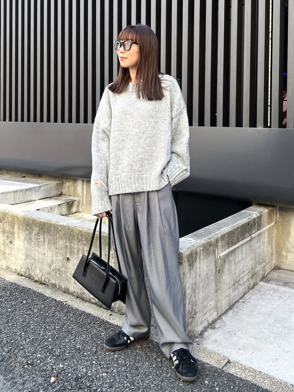 グレー系のニット/セーター、グレー系のスラックス、ブラック系のスニーカーを着用したレディースの秋コーディネートの3枚目の写真