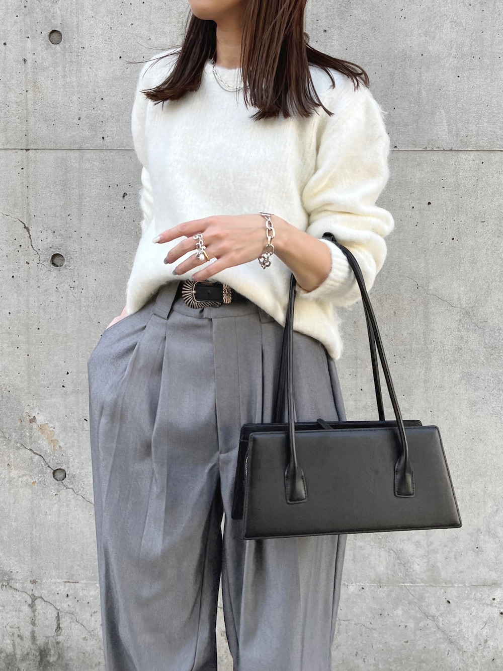 ホワイト系のニット/セーター、グレー系のスラックス、ブラック系のハンドバッグを着用したレディースの秋コーディネートの4枚目の写真