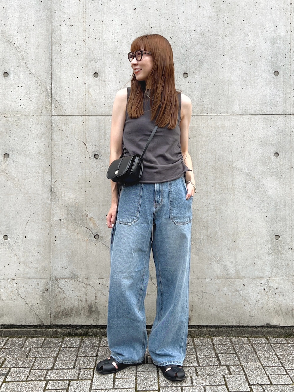ブラック系のサンダル、グレー系のトップス、ブルー系のデニムパンツを着用したレディースの夏コーディネートの2枚目の写真