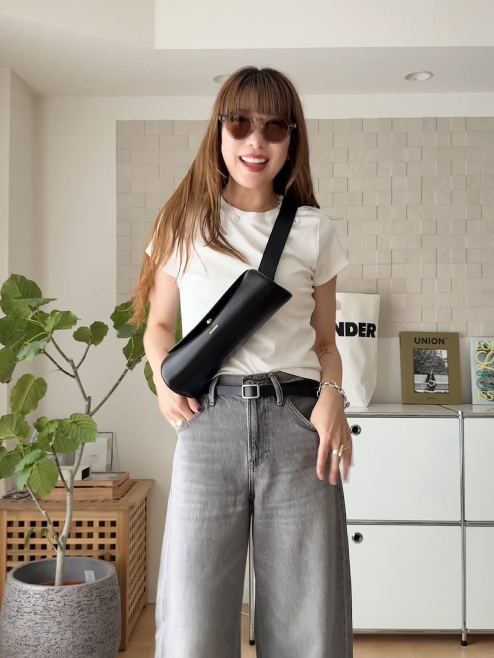 ブラック系のショルダーバッグ、ブラック系のサンダル、グレー系のデニムパンツを着用したレディースの夏コーディネートの3枚目の写真