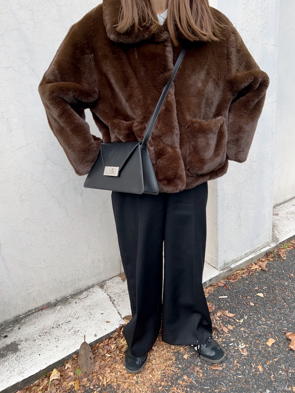 ブラウン系のブルゾン、ブラック系のショルダーバッグ、ホワイト系のTシャツ/カットソーを着用したレディースの冬コーディネートの5枚目の写真