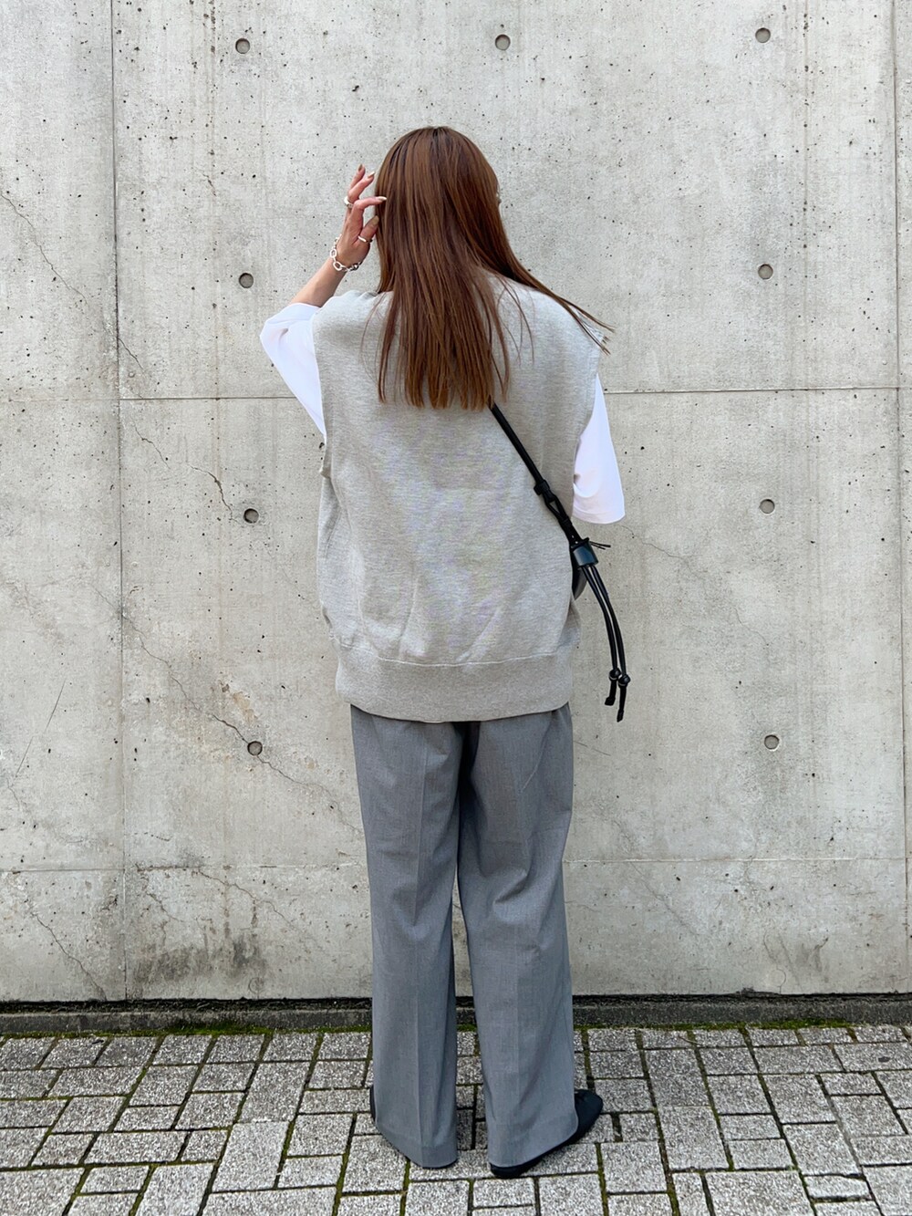 グレー系のニット/セーター、ブラック系のスリッポン、ホワイト系のTシャツ/カットソーを着用したレディースの春コーディネートの3枚目の写真