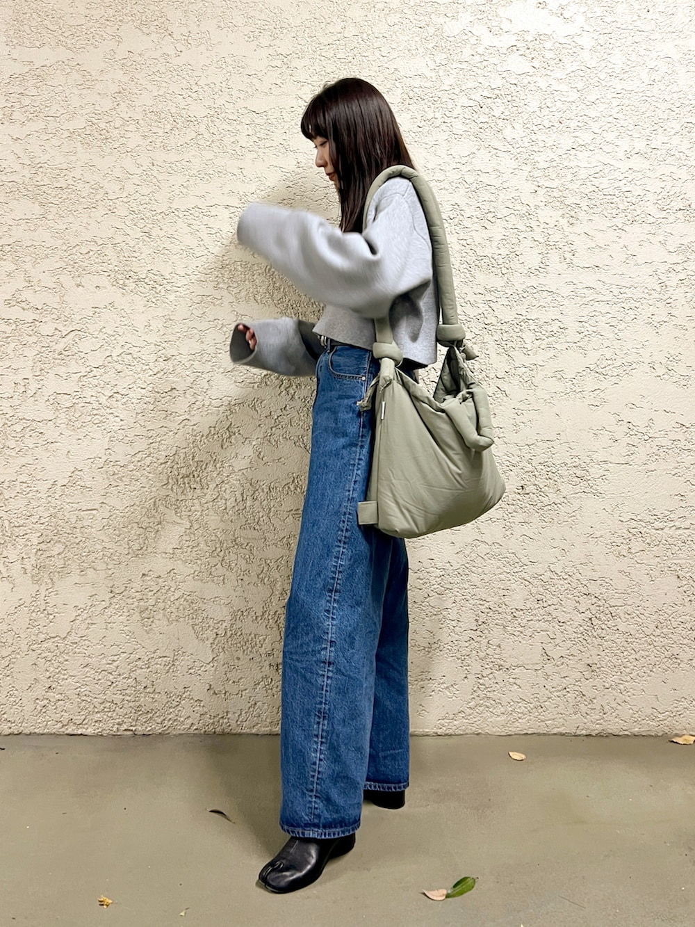グレー系のニット/セーター、ブルー系のデニムパンツ、ブラック系のブーツを着用したレディースの冬コーディネートの3枚目の写真