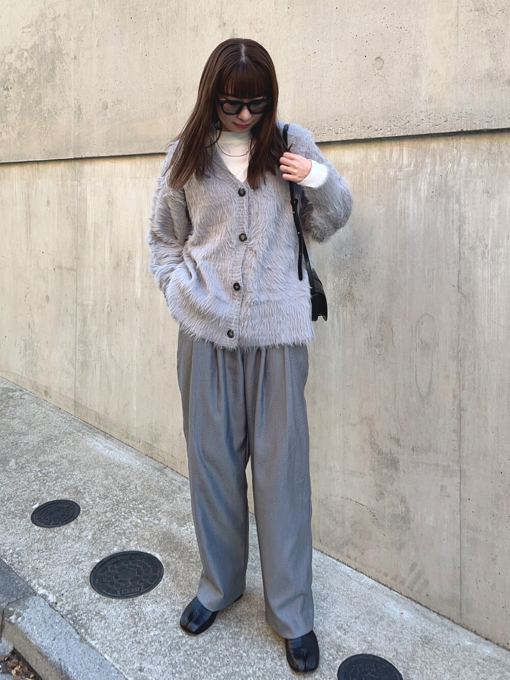 グレー系のカーディガン/ボレロ、ホワイト系のTシャツ/カットソー、ブラック系のショルダーバッグを着用したレディースの冬コーディネートの2枚目の写真