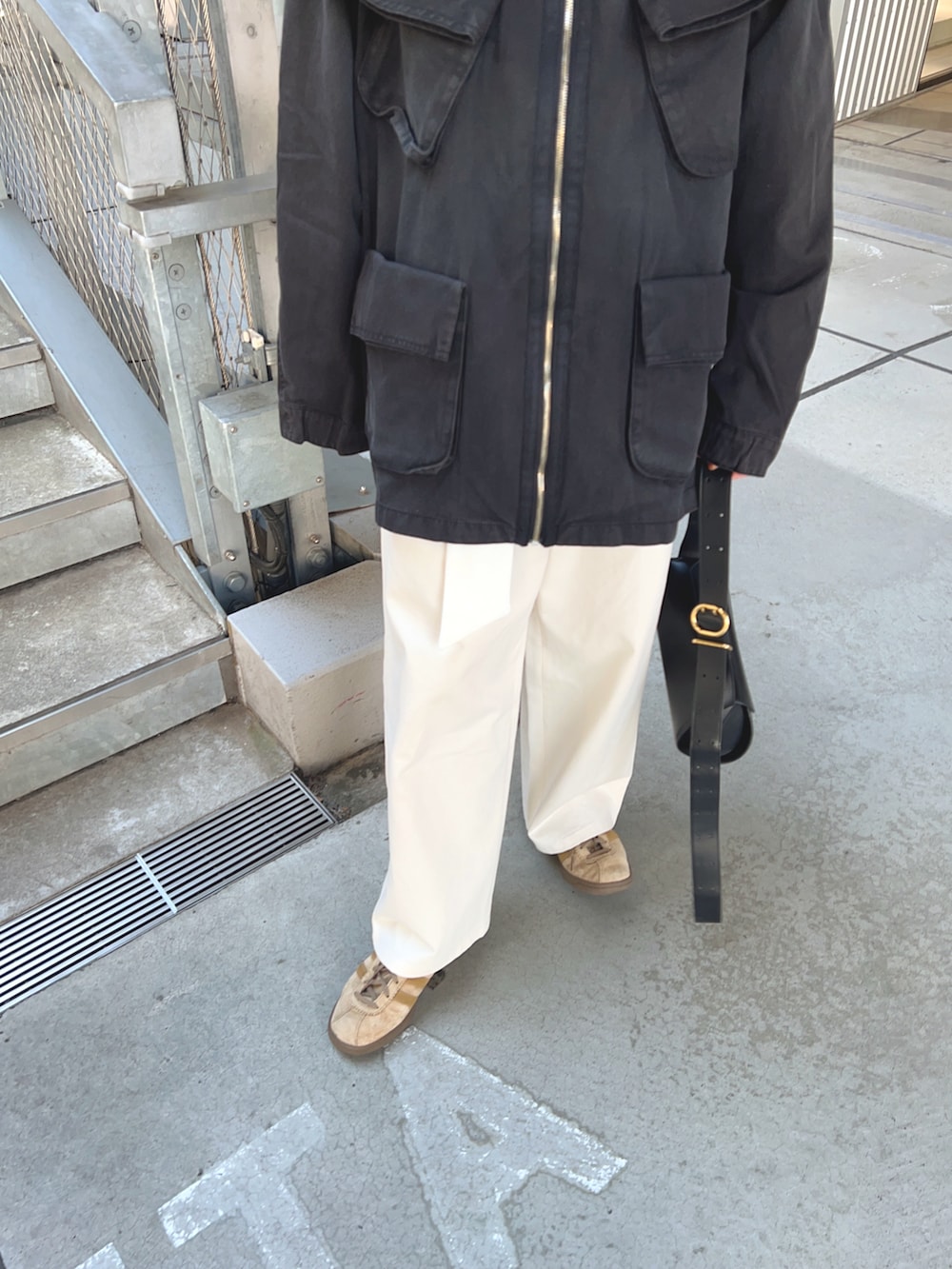 ブラック系のジャケット/アウター、ホワイト系のチノパンツ、ブラック系のショルダーバッグを着用したレディースの春コーディネートの5枚目の写真