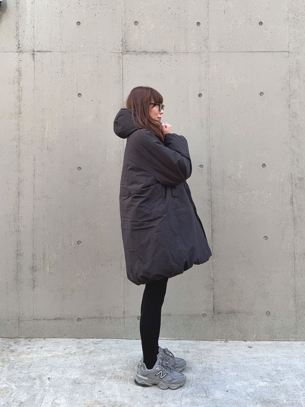 ブラック系のダウンジャケット/コート、ベージュ系のショルダーバッグ、グレー系のスニーカーを着用したレディースの冬コーディネートの2枚目の写真